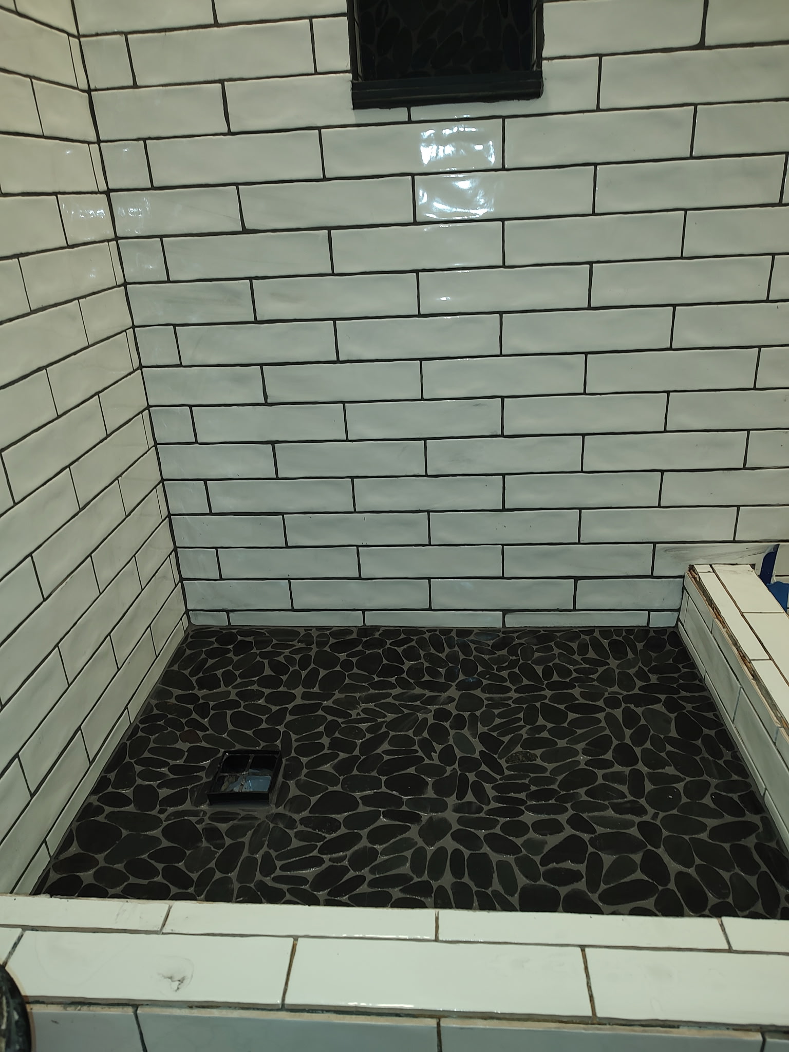 Custom shower with subway tile and pebble flooring